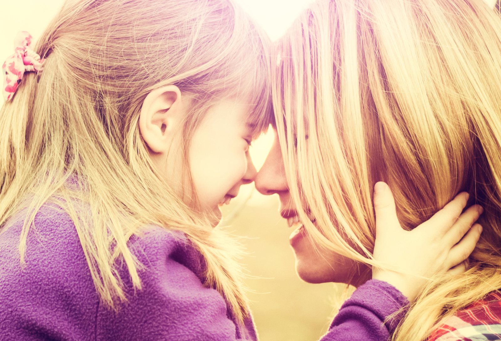 A young girl and her caregiver touching foreheads and smiling