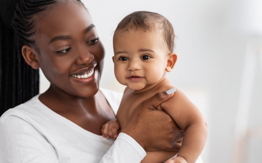 An infant care specialist holding a smiling baby