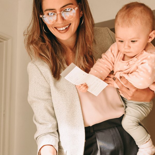 A carer holding a baby while reading a document