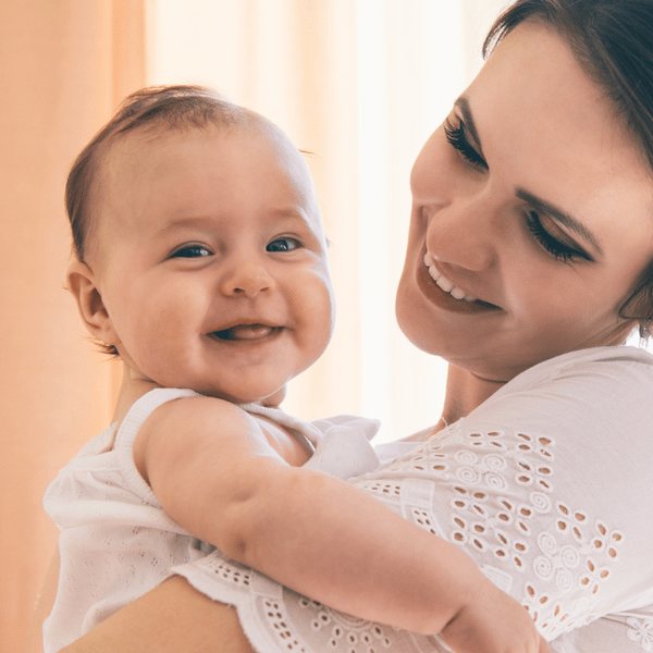 A smiling baby held close by a carer