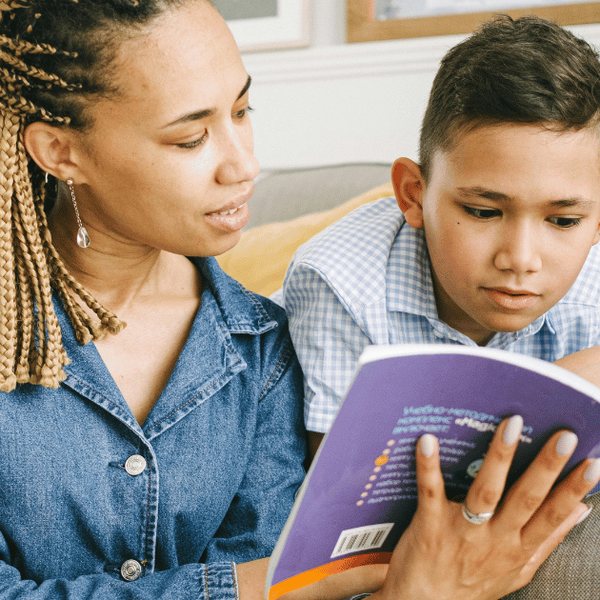 A carer reading a book with a boy on the couch