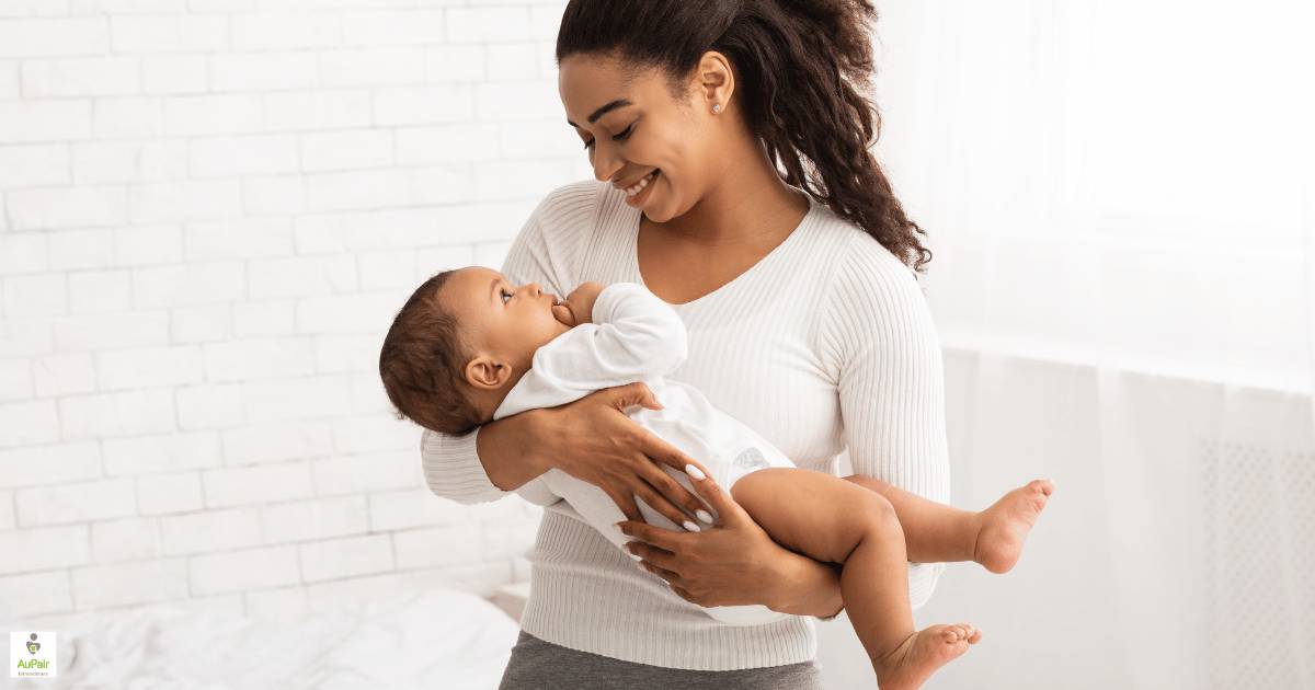 An infant care specialist smiling at a baby cradled in her arms